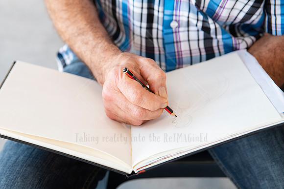 Close-up of artist sketching in a blank book, storytelling image for Artwalk’s creative process highlights.
