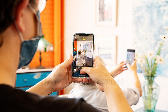 Hands holding up phones to capture exhibition work, shot taken during gallery interaction at Sunset Framing & Gallery.