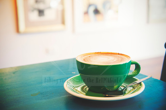 Flat lay of coffee in a green cup on blue table at Sunset Framing & Gallery café in Port Macquarie.