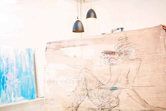 Art canvas hanging across the wall, featuring sketched lines of faces and bodies under gallery lights.