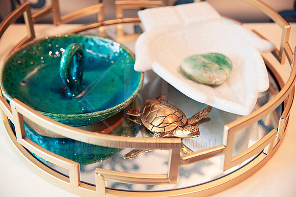 Teal dishware and small sculptural items styled on a decorative tray.