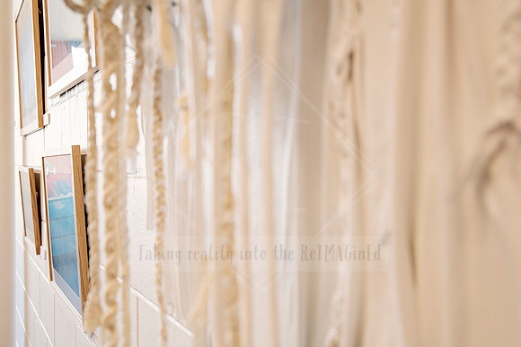 Macrame curtain detail and gallery wall with framed artworks, styled interior capture from Sunset Framing & Gallery.