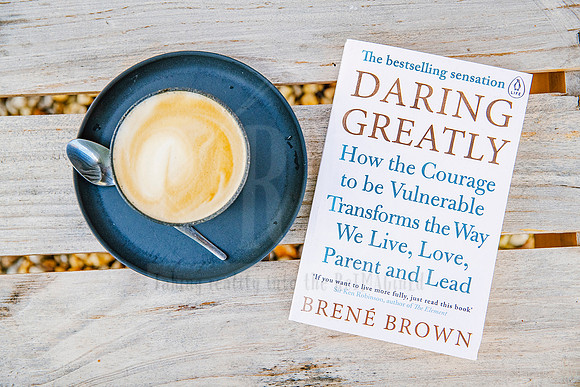Flatlay of espresso, “Daring Greatly” book, and wooden table backdrop, calm and intentional brand content for Bron Watson & Co.