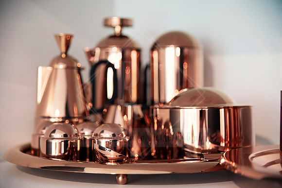 Copper coffee and tea canisters with metallic sheen on a circular tray.