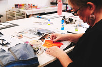 Hands creating paper collage artwork during a workshop.
