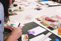 Close-up of hands working on a collage artwork.