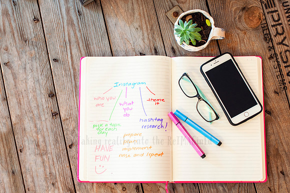Desk flat lay with notebook, coloured pens, phone and glasses—visual content created for small business planning and branding.