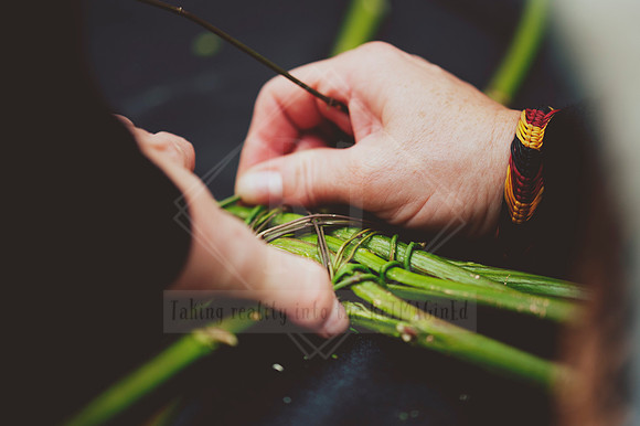Tight shot of fingers weaving green reeds, showing detailed craftsmanship at a Mid North Coast maker event.