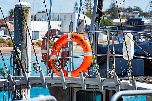 Close-up of docked fishing rods and life ring on a commercial charter vessel.