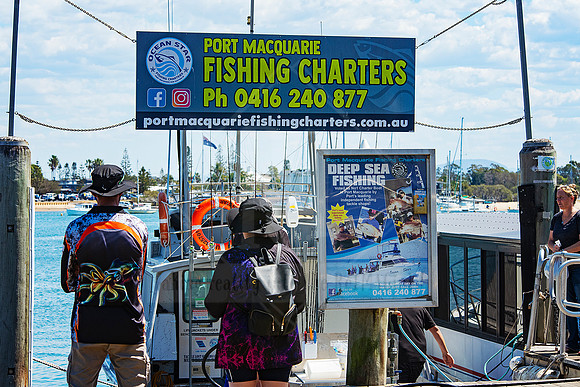 People gathered under a Port Macquarie Fishing Charters sign before boarding.