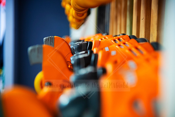 Close-up of orange rental skates lined up in wooden rack with soft depth of field.
