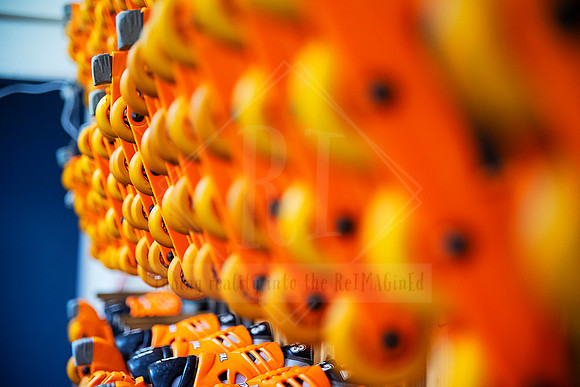 Close-up of orange rental skates lined up in wooden rack with soft depth of field.