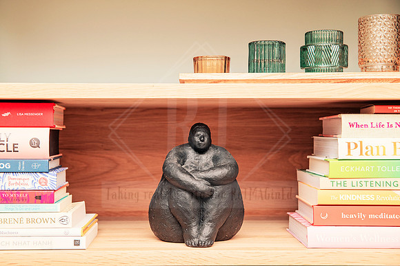 Bookshelf with a ceramic seated figure sculpture, books, and soft lighting.