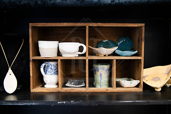 Shelf with artisan ceramic mugs and bowls, styled for Artwalk’s celebration of handmade craftsmanship.