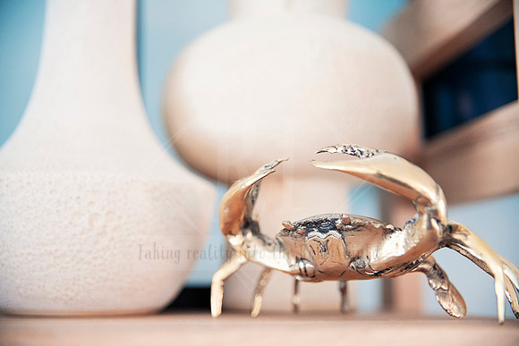 Decorative gold crab ornament on shelf with textured white vases.