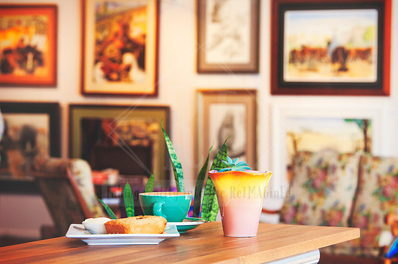 Cozy café table setting with coffee and cake in a local Port Macquarie gallery, photographed for business promotion.
