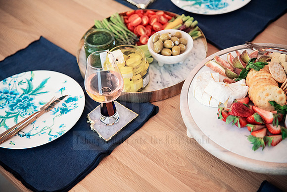 brie cheese wheel with sides and wine glass set on navy napkin and aqua dinnerware.