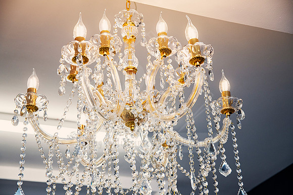 Elegant crystal chandelier with golden accents hanging in the salon at Lovely Locks Hairdressing.