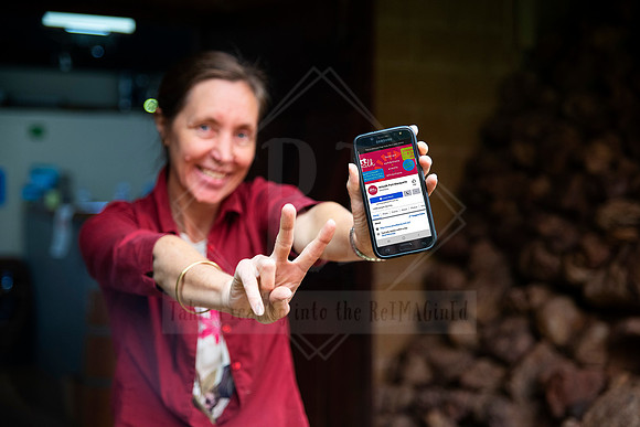Smiling woman holding Artwalk website on phone while gesturing ‘peace’, captured for digital and print use.
