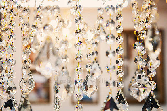Crystal chandelier strands with rainbow reflections and blurred background.