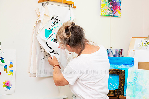 Creative woman painting onto clothing for wearable art, photographed as part of studio-based content shoot.