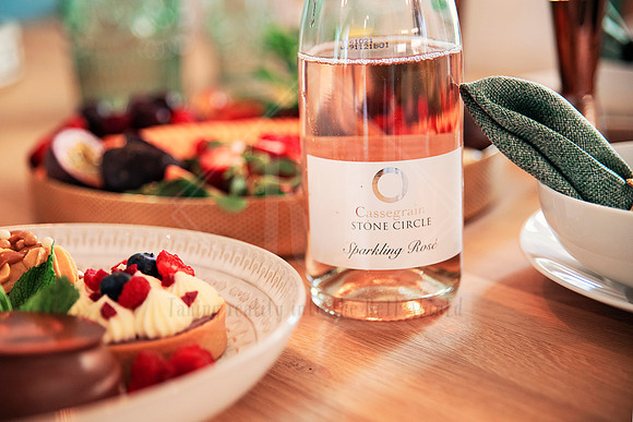 Close-up of a wooden platter and chilled rosé with breakfast foods in warm morning light.