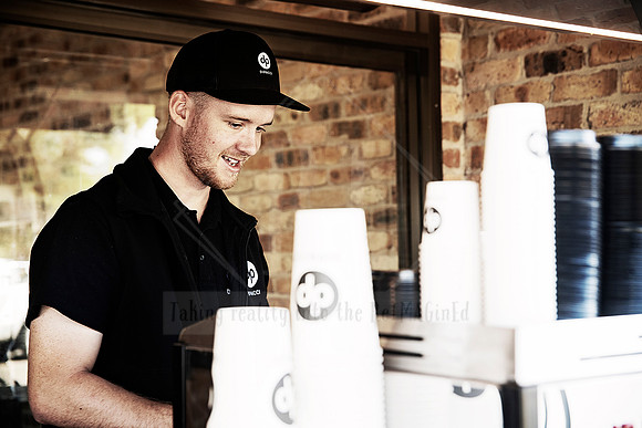 Barista in black uniform smiling while preparing coffee at Dipacci Coffee PMQ.