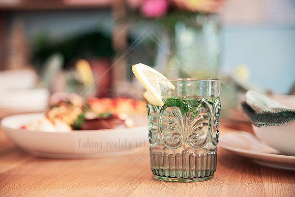 Mint and lime drink on a timber table with grazing platter in soft background blur.