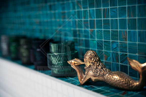 Green mosaic bathroom tiles with brass sea creature ornament and green glass accessories.