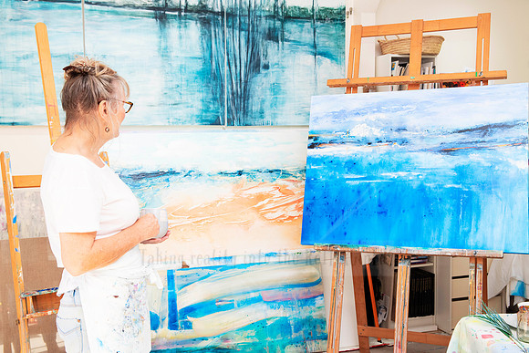 Artist painting abstract seascape in studio, content created to highlight local art practice and creative process.