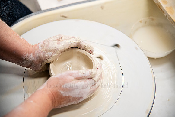 Hands shaping clay on a pottery wheel in action shot, captured for Artwalk’s behind-the-scenes storytelling.