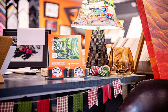 Sunset Framing & Gallery counter styled with lamp, business cards, gift items, and gingham bunting.