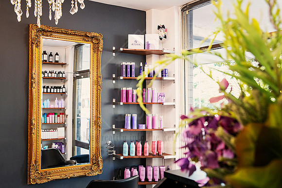 Shelving with hair products reflected in a gold mirror, framed by decorative lighting.