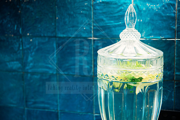 Elegant glass carafe filled with mint-infused water against a rich blue tiled background.