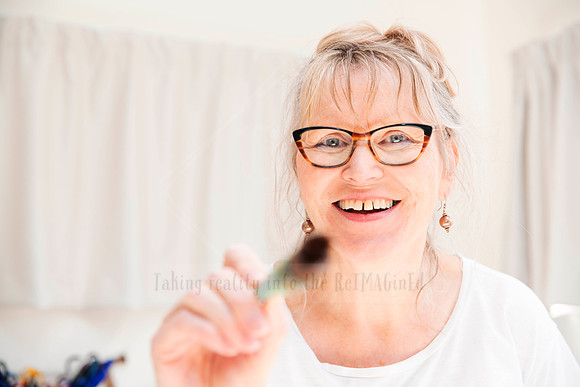 Portrait of smiling artist holding paintbrush toward camera, captured for Artwalk media campaign to convey warmth and approachability.