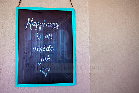 Wall sign reading “Happiness is an inside job” in handwritten script, part of Bron Watson & Co’s positive messaging series.