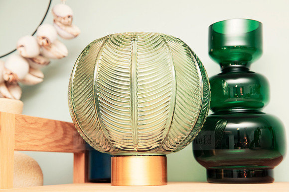 Mid-century shelf styled with green glass vases and a ribbed leaf-patterned lamp.