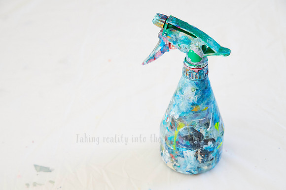 Close-up of paint-covered spray bottle in artist studio, styled for behind-the-scenes visual storytelling.
