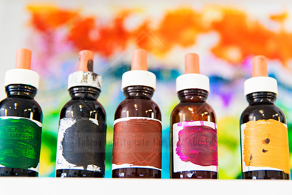 Row of vibrant ink dropper bottles lined up with colourful labels.