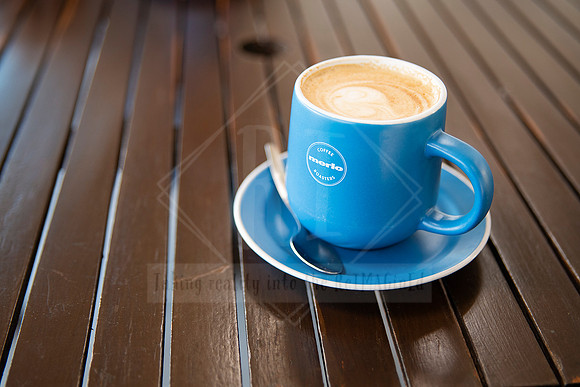 Close-up of latte in blue cup on timber table, styled image for Artwalk café culture feature.