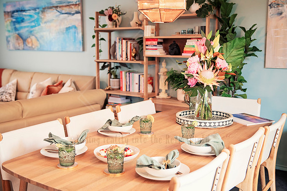 Cozy dining area styled with a vase of lilies, books, and vintage tableware.
