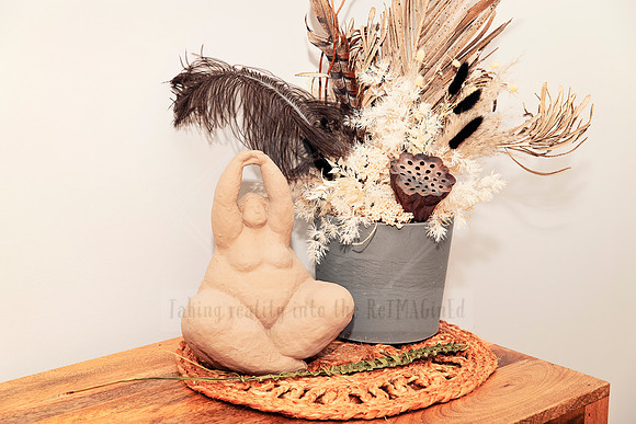Feminine ceramic sculpture with a neutral-toned dried flower arrangement.