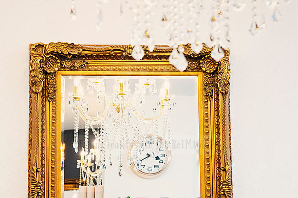Golden-framed mirrors reflecting chandelier light and salon shelving.