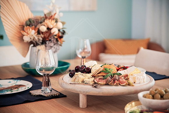 Large grazing platter on timber table with glasses of wine and teal feature décor.