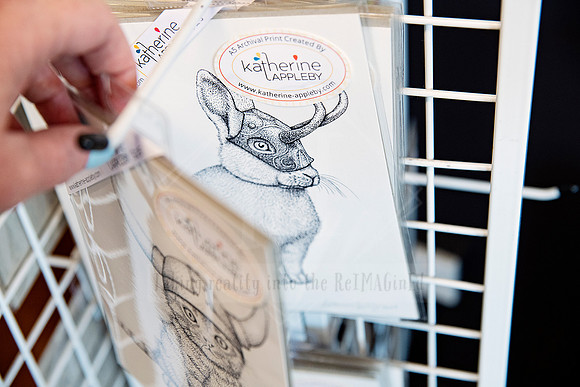 Hand selecting a vintage-style bunny greeting card from a wire display rack.