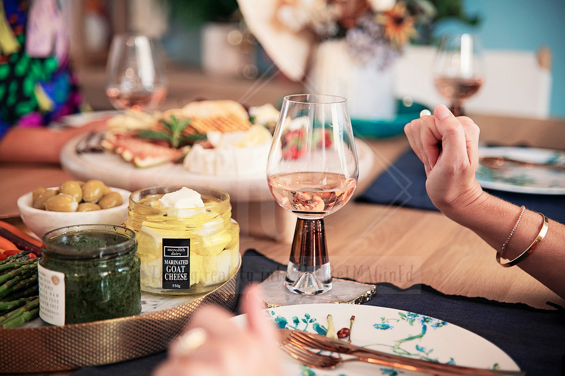 Guests enjoying a styled grazing table with olives, dips, and artisan crackers.