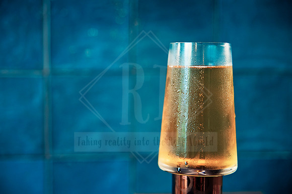 Minimalist image of a single beer glass with rich teal background.