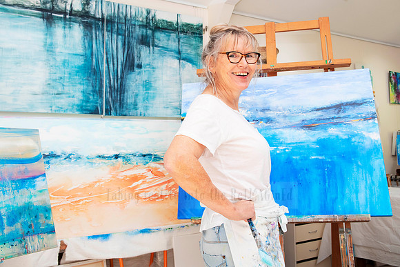 Confident artist posing with completed painting in studio, captured for portfolio and creative brand storytelling.