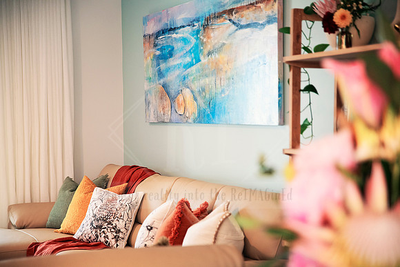 Relaxing lounge space with plush pillows and beach-inspired wall art.