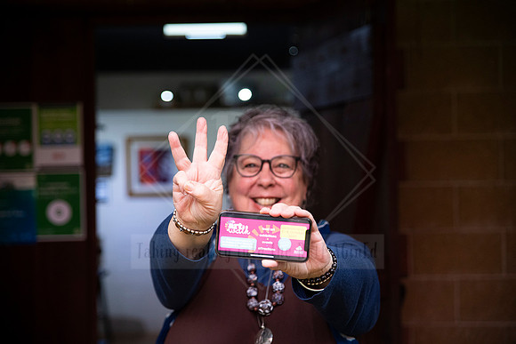 women proudly holding up Artwalk event passes and holding up 3 fingers, photographed for promotional material.